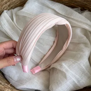 Detailansicht eines weichen rosa plissierten Satin-Haarreifens für elegantes Haarstyling