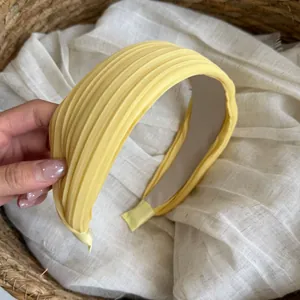 Nahaufnahme eines gelben plissierten breiten Stirnbands mit eleganter Stofftextur