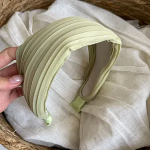 Detail eines hellgrünen, gefalteten Satin-Stirnbands für Damen mit eleganter Textur
