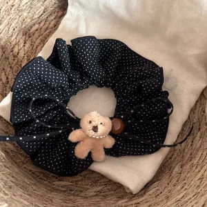 Vue détaillée d'un chouchou à pois noirs avec un petit ours en peluche et des rubans