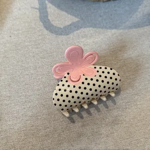 Primo piano del dettaglio del fiore rosa su un fermaglio per capelli a pois in acetato