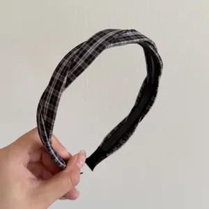 Detailed view of black and white plaid twisted headband showing fabric texture and teeth