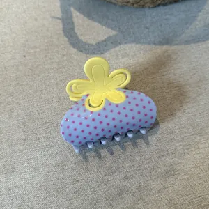 Primo piano di una molletta per capelli azzurra a pois rosa con fiore giallo
