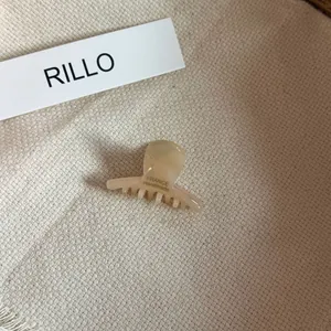 Close-up of a small cream acetate hair claw clip on a textured fabric background