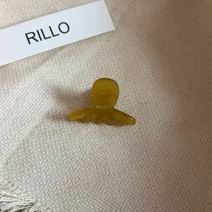 Close-up of small mustard yellow acetate hair claw clip with France Handmade engraving.
