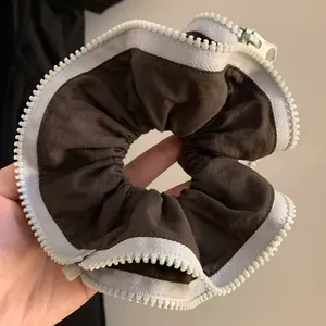 Detailed close-up view of a unique brown scrunchie with white zipper trim