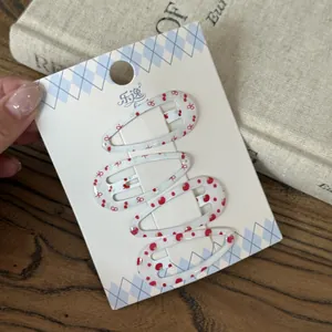 Vista detallada de cuatro mini pinzas para el cabello con estampados de cereza y fresa.