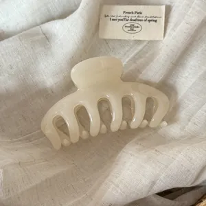 Detail of a large cream-colored Korean style acrylic hair claw clip on white linen