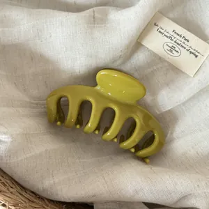 Macro view of minimalist large olive green glossy hair claw clip on linen fabric