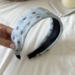 Close-up detail of retro light blue wide headband with brown polka dot pattern