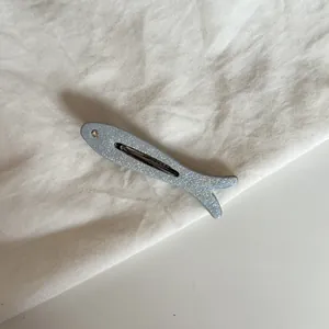 Primer plano detallado de un pasador de pelo de pez azul con purpurina y ojo de cristal