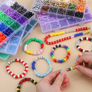 Mains enfilant des perles colorées de 9x6mm d'un kit complet de bijoux DIY à 24 cases.