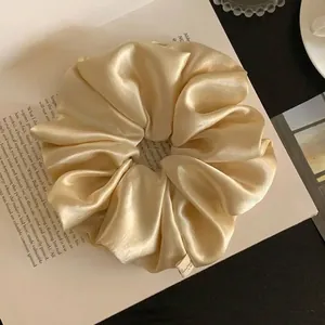 Elegant champagne satin oversized scrunchie hair accessory on a book background