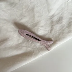 Detalle de una pinza para el pelo con forma de pez rosa brillante y un pequeño ojo de cristal