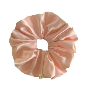 Elegant pink satin scrunchie with handmade tag for hair accessories on white background
