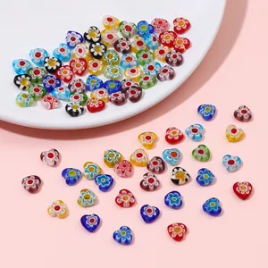 Detailed macro shot of various colorful millefiori pattern heart beads scattered on pink surface