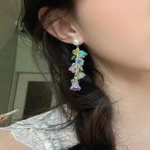 Detailed view of colorful lily of the valley crystal tassel earrings worn on a model's ear