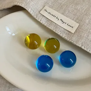 Detailed macro shot of transparent colorful resin stud earrings on a ceramic plate