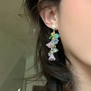 Close-up of colorful lily-of-the-valley crystal tassel earrings shown on model ear.