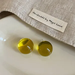 Macro view of yellow transparent resin stud earrings on minimalist linen background