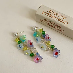 Detailed view of colorful lily of the valley crystal tassel earrings on a textured surface