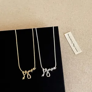 Detail van gouden en zilveren slangenhangers op een zwarte displayvoet.