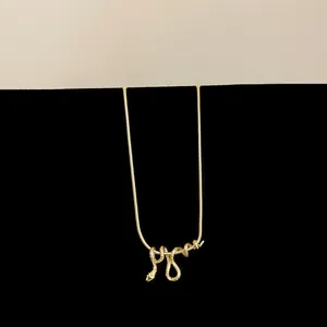 Macro-detailweergave van de ingewikkelde goudkleurige slangenhanger aan een slangenketting.