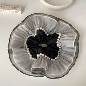 Vue détaillée du chouchou géant en organza gris orné d'une élégante bordure perlée.