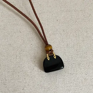 Detailopname van handtas hanger ketting met natuurlijke tijgeroog kraal