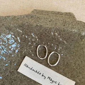 Macro delle orecchini a cerchio ovali in argento su una base di pietra naturale grigia.