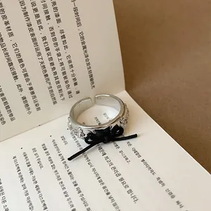 Primo piano di un anello celeste argentato con un delicato fiocco di corda nera.