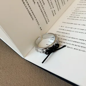 Dettaglio di anello aperto argento con incisione di pianeta e fiocco in corda nera.