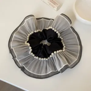 Vue détaillée d'un grand chouchou en organza gris avec des perles et un centre en satin noir