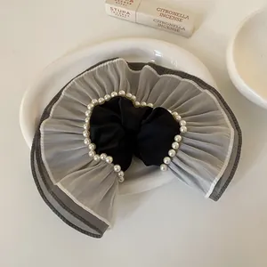 Détail rapproché des volants en organza gris et des perles sur ce grand chouchou