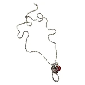 Zilveren ketting met vintage knoop hanger en rood-wit gestippelde bedel kraal.