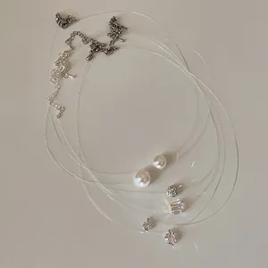 Detailed close-up of minimalist fish line necklaces with elegant pearl and zircon charms