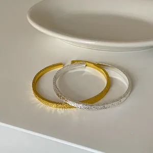 Nahaufnahme goldener und silberner strukturierter Armreifen mit schimmerndem Hammerschlag-Finish