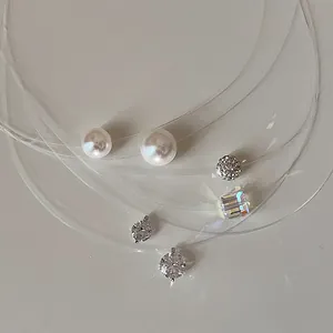 Close-up detail of minimalist fishing line necklaces with pearl and zircon pendants