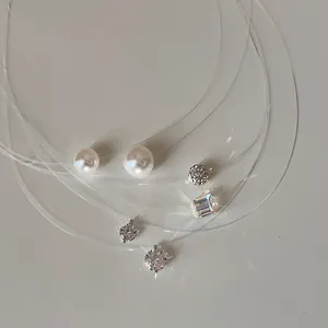 Close-up detail of minimalist invisible fish line necklaces with pearl and zircon pendants