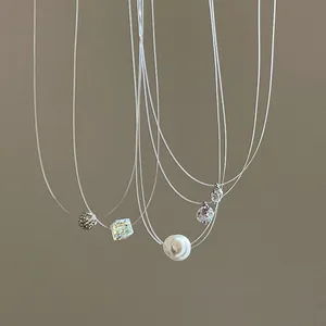 Close-up detail of minimalist fishing line necklaces with pearl, zircon and laser cube
