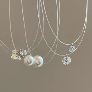 Close-up of various pendants on a minimalist transparent fishing line necklace style