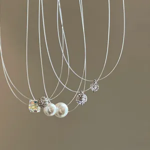Detailed view of minimalist fishing line necklaces with pearl and zircon pendants.