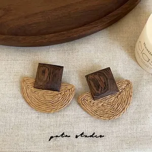 Detailed macro view of geometric woven straw and dark wood patchwork stud earrings