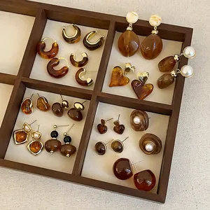 Collection of brown resin earrings in a wooden tray with vintage amber and pearl details