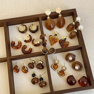 Detailed view of Maillard brown resin earrings in various vintage styles displayed in a wooden tray