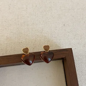 Close-up detail of stylish double heart resin earrings in warm brown amber finish
