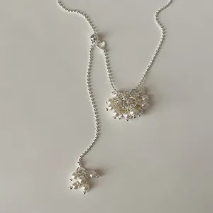 Detailed close-up of elegant white pearl grape bunch pendant on silver ball chain