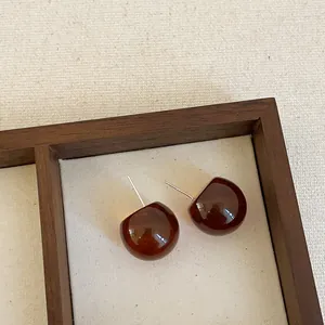 Detailed macro view of translucent coffee brown resin stud earrings on a textured canvas background