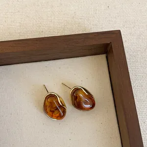 Detailed view of Maillard brown resin earrings with gold bezel in a wooden frame