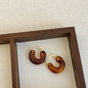 Detail view of Maillard brown resin hoop earrings displayed in a wooden jewelry box.